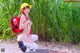 A woman in a yellow hat is sitting on the ground with a red backpack.