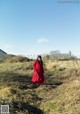 A woman in a red dress walking through a field.