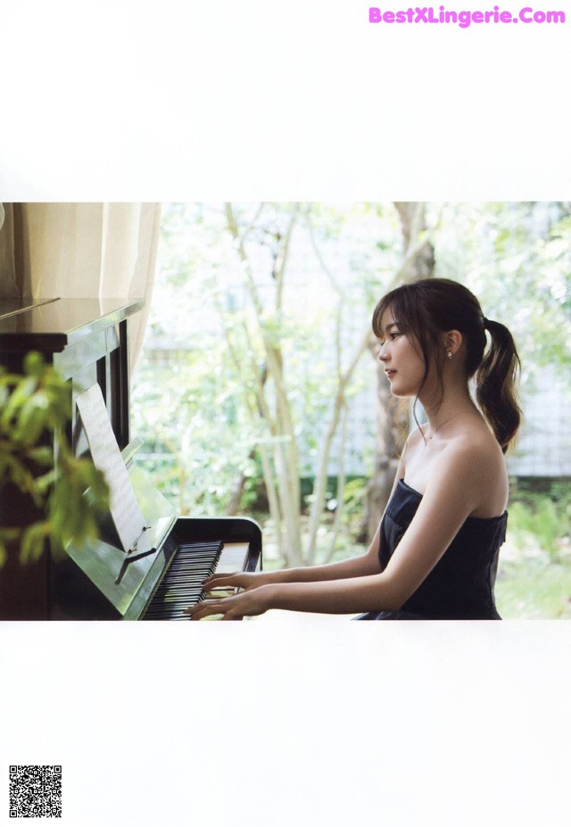 A woman in a black dress playing a piano.