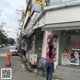 A woman walking down the street in front of a store.