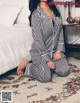 A woman sitting on the floor in pajamas in a bedroom.