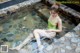 A woman in a green bathing suit sitting in a pool of water.