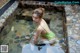 A woman in a green bathing suit sitting in a pool of water.