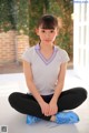 A young woman sitting on the ground with her legs crossed.