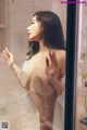 A naked woman standing in front of a glass door.