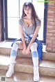 A woman sitting on the steps of a brick building.