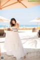 A woman in a white dress standing on a beach.