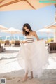 A woman in a white dress standing on a beach.