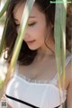 A woman in a white and black dress standing in tall grass.