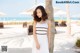 A woman in a white dress standing next to a palm tree.