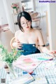 A woman sitting at a table with a bunch of art supplies.