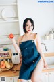 A woman sitting on a kitchen counter holding an apple.