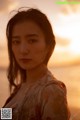 A woman standing on a beach at sunset. 