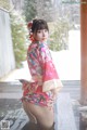 A woman in a pink kimono is posing in the snow.