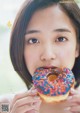 A young woman eating a donut with sprinkles on it.