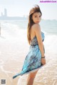 A woman in a blue dress standing on the beach.