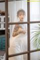 A woman in a wedding dress standing in front of a window.