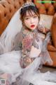 A woman with tattoos sitting on a couch wearing a wedding dress.