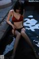 A woman in a red bra and black stockings sitting in a pool.