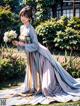 A woman in a long dress holding a bouquet of flowers.