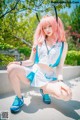 A woman with pink hair sitting on a concrete ledge.