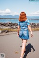 A woman walking down a road next to a body of water.